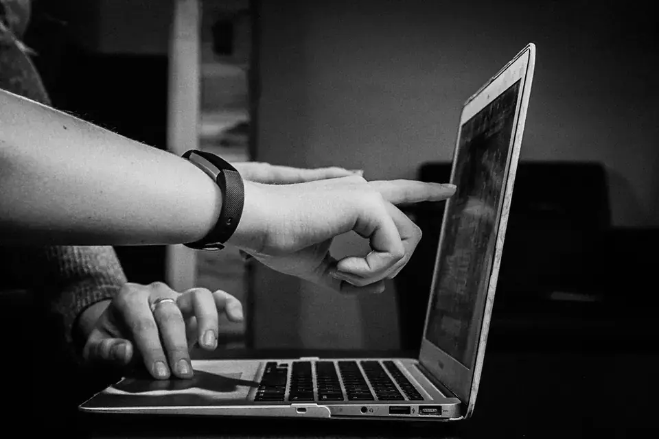 Two people reviewing a document on a laptop, black and white