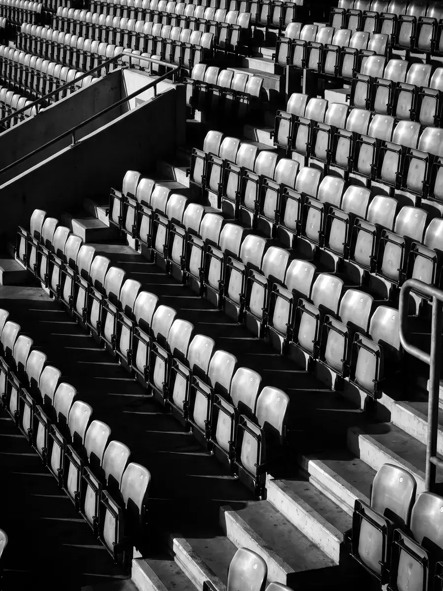 Empty stadium seats in raking light, black and white